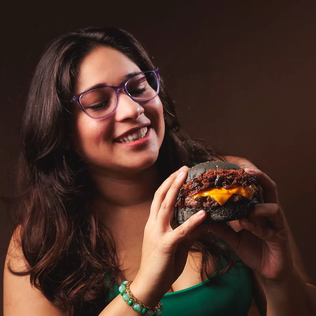 Cliente da Cash Burger segurando um burger de pão preto com cheddar