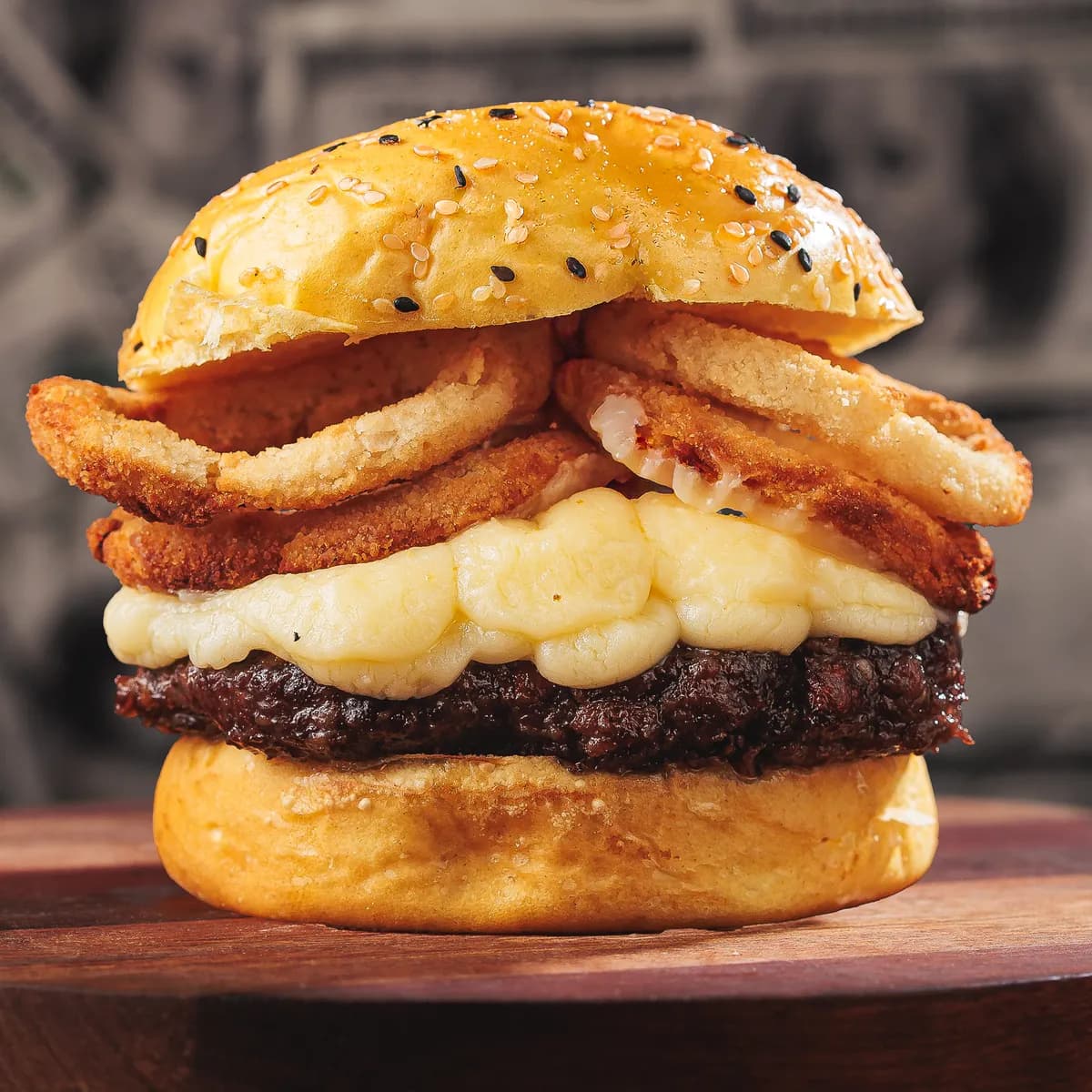 Mentalidade: burger de pão amarelo com queijo derretido e onion rings